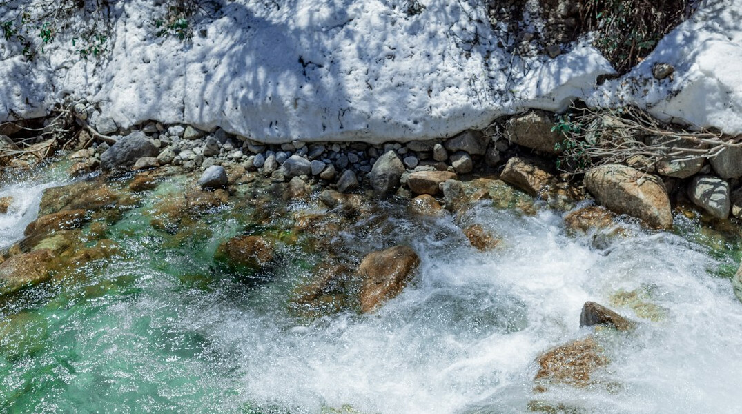 Clear alpine river with water testing equipment on rocks